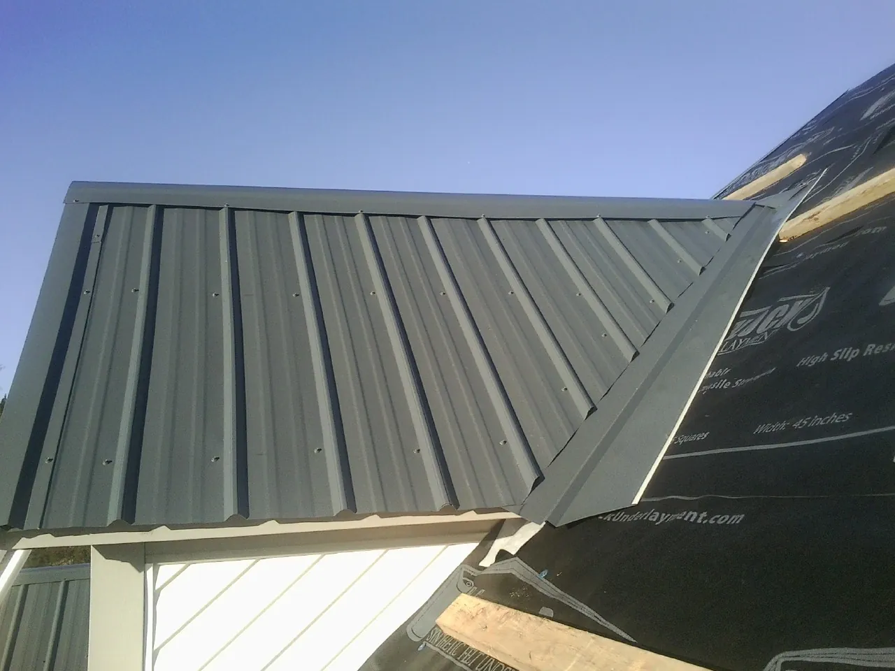 Gray metal roof panels going on over a garage gable in High Ridge