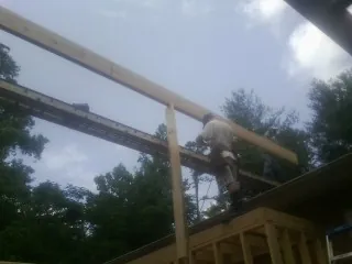 Carpenter setting a ridge beam over a new addition frame — Ice Dam Removal by Roofing Brothers in High Ridge