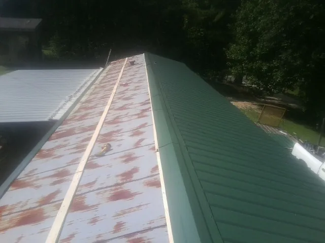 Old rusted panels beside newly installed green metal roofing — Wind Damage Roof Repair by Roofing Brothers in High Ridge