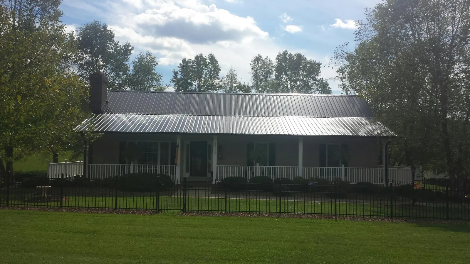 Gray metal roof on a brick ranch with a full width front porch — Gutter Guard Installation work by our crew in High Ridge