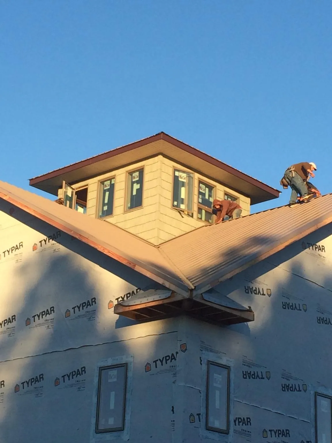 Roofers working around a rooftop cupola on a new metal roof at sunset — Roof Waterproofing in High Ridge by Roofing Brothers